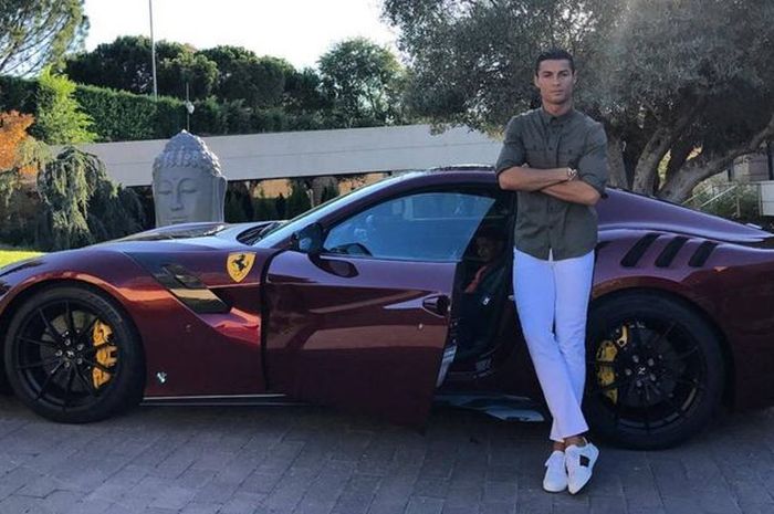 Cristiano Ronaldo yang dilempar botol Coca-cola saat selebrasi gol kedua melawan Prancis sedang berpose di samping Ferrari F12 TDF.