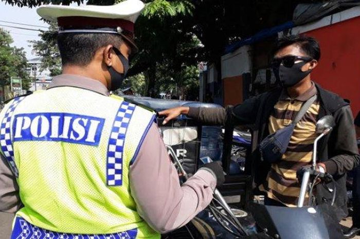 Personel Satlantas Polrestro Jakarta Timur saat menindak pengemudi motor yang tak mengenakan helm, Selasa (28/7/2020)  