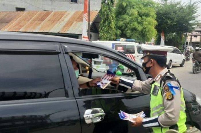 Personel Satlantas Polres Lhokseumawe, membagika brosur bertuliskan tentang Adaptasi Kebiasaan Baru (AKB) saat operasi Patuh Seulawah 2020 di Pos Lantas Cunda, Kecamatan Muara Dua, Kota Lhokseumawe, Senin (03/08/2020).