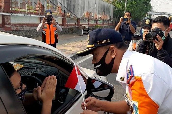 Petugas membagikan bendera ketika melakukan sosialisasi ganjil genap di Jalan Gunung Sahari, Pademangan, Jakarta Utara, Rabu (5/8/2020). 