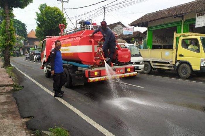 Dinas Damkar Gianyar membersihkan tumpahan solar di jalan raya Wanayu, Bedulu, Kecamatan Blahbatuh, Gianyar, Sabtu (1/8/2020). 