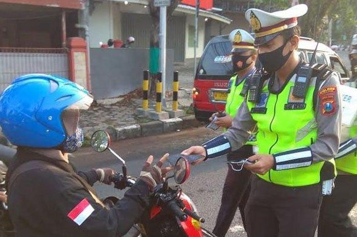 Anggota Satlantas Polres Gresik membagikan masker kepada pengguna jalan.