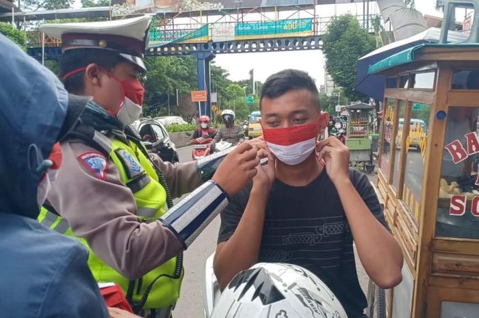 Personel Ditlantas Polda Aceh membagikan masker Merah Putih ke pengguna jalan.