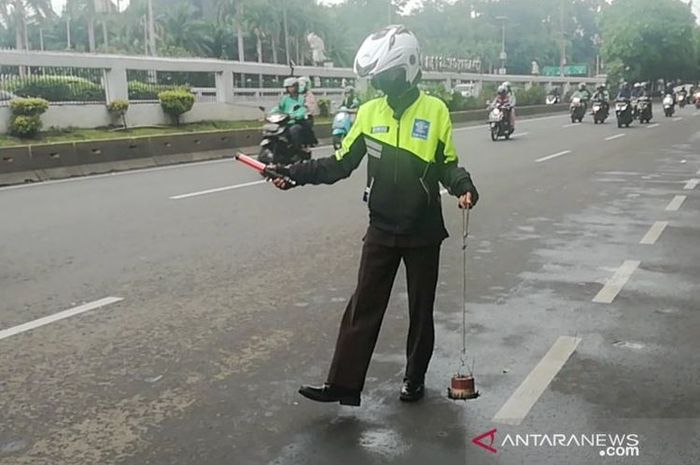 Relawan Sapu Bersih (Saber) Abdul Rohim melakukan penyapuan dengan magnet saat razia ranjau paku di Jalan Gatot Subroto, Jakarta Selatan