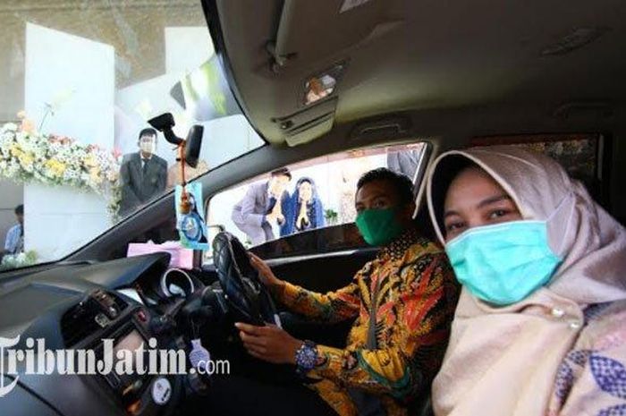Tamu undangan melakukan selfie bersama pengantin dalam pesta resepsi pernikahan yang digelar secara drive thru di di halaman parkir Hotel Aston Banyuwangi, Kamis (13/8/2020).