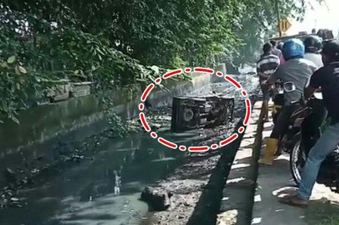 Sejumlah warga menyaksikan mobil pikap yang terjun ke saluran air di Kertapati, Palembang.  