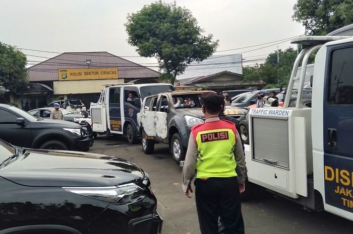 Petugas menderek dua mobil yang terbakar, dua mobil dalam kondisi pecah kaca dan satu bus operasional di Mapolsek Ciracas, Sabtu (29/9/2020)