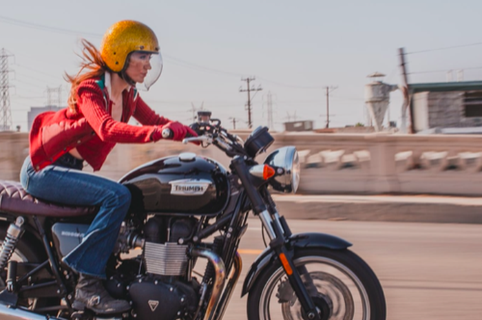 Ilustrasi lady biker naik motor siang hari