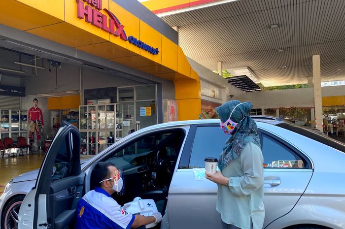 Mekanik SPBU Shell meletakkan alat desinfeksi interior mobil di mobil pelanggan Shell.