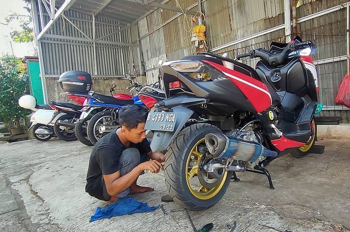 Ilustrasi mekanik bengkel sedang bongkar sokbreker motor