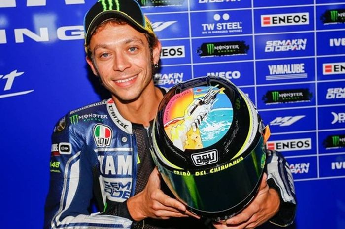 Valentino Rossi memegang helm yang dipakai untuk balap
