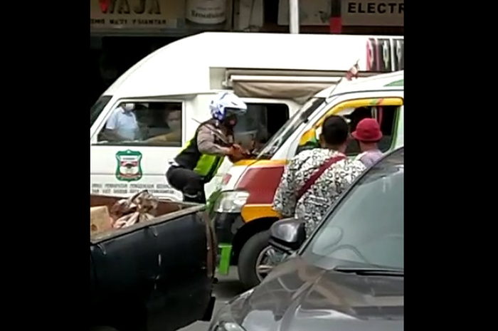 Foto: Tangkapan layar seorang Polantas menggantung diatas Angkutan umum di Jalan Sutomo Pematangsiantar, Senin (15/9/2020).