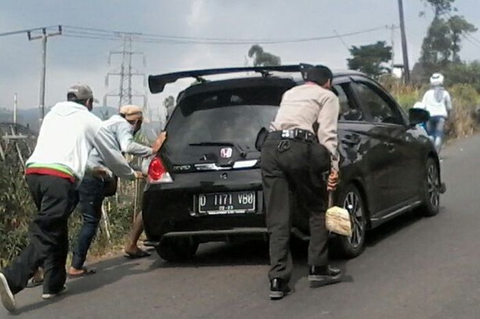 Tampak petugas dan warga tengah membantu mendorong serta mengganjal kendaraan pemudik yang mogok di jalur tanjakan Kamojang-Ibun. (Foto Humas Polda Jabar )  