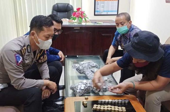 ursam Romdoni, pedagang mainan dan aksesoris wanita asal Kelurahan Kertosari, Kecamatan Ponogoro, Kabupaten Ponorogo membayar pajak mobil dengan uang koin yang dikumpulkan dalam setahun.