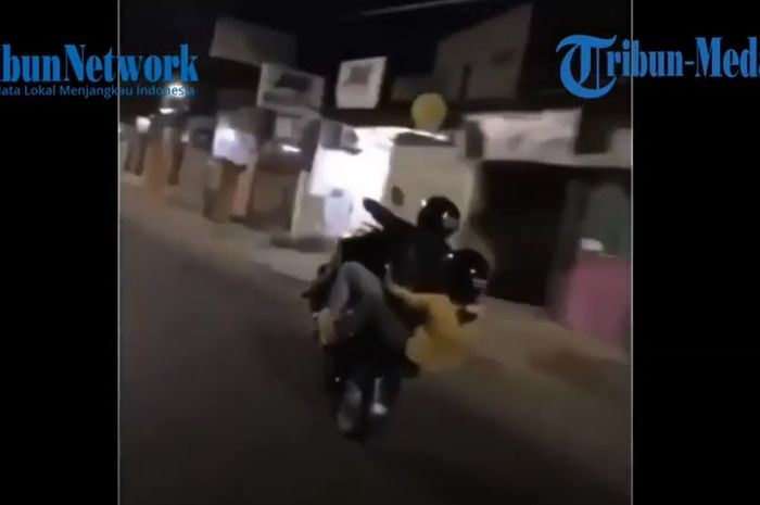 Aksi sepasang kekasih melakukan aksi wheelie di jalan raya