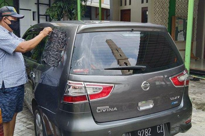 Pemilik mobil Grand Livina Andreas Lukito sedang membersihkan pecahan kaca kiri belakangnya setelah dipecah di Jalan Jati Barat.