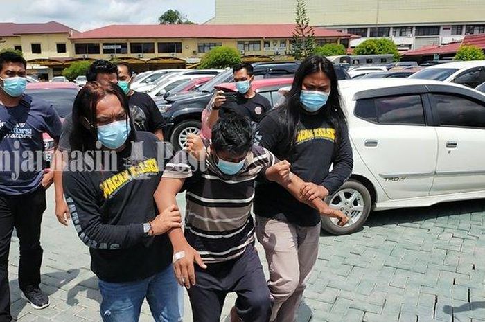 IR, pelaku begal sopir mobil sewaan yang ditangkap di Banyuwangi, dipapah petugas saat tiba di Polda Kalimantan Selatan, Rabu (2/122020). 