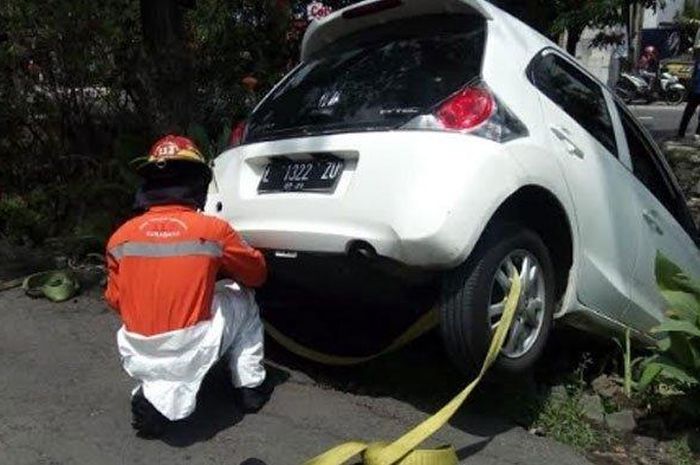 Honda Brio gelantung di bibir sungai Wiyung, kota Surabaya akibat pengemudi salah masukan gigi persneling