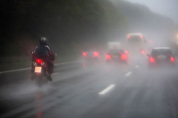 ilustrasi pemotor berkendara di kondisi hujan