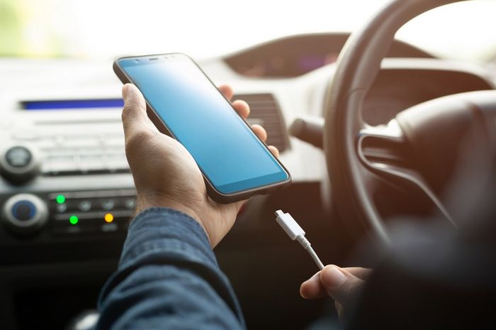 Ilustrasi mengisi daya baterai ponsel di mobil.