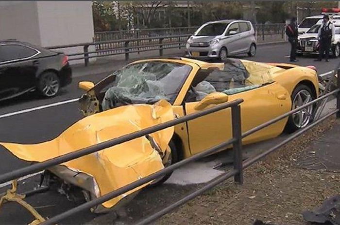 Ferrari kuning yang ringsek bagian depan dan kaca depan pecah.