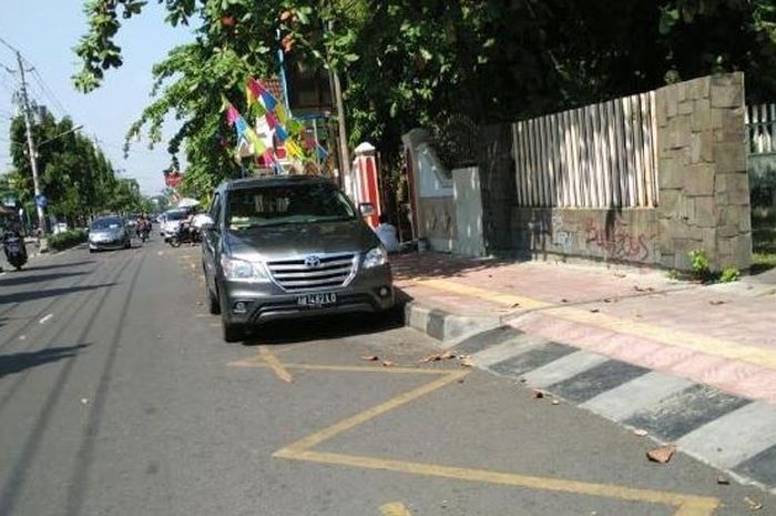 Ilustrasi kendaraan parkir di atas marka berbiku