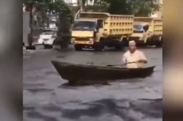 Seorang kakek mengayuh perahu di jalanan  banjir di jalan protokol Banjarmasin (Youtube Tribun Timur)