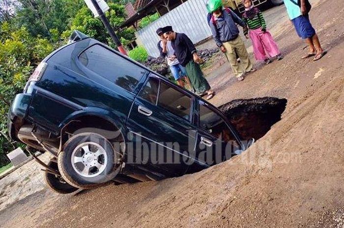 Mobil Kijang terperosok ke dalam lubang di jalan Kaliwiro Wonosobo, Selasa (16/2/2021). 