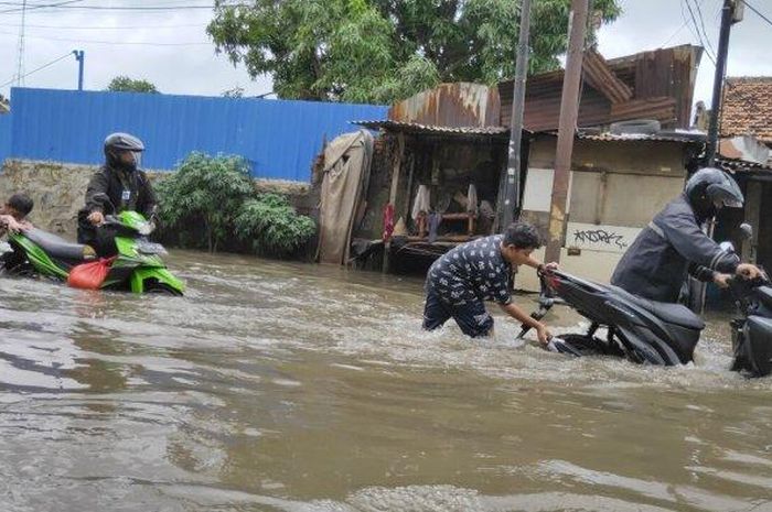 Di lokasi, anak - anak turut membantu para pemotor yang mendorong kendaraannya menerobos genangan. Para anak - anak ini membantu menutup lubang knalpot dengan tangan guna menghalangi air masuk. 