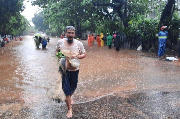 Warga menangkap ikan saat banjir di Jalan TB Simatupang, Jakarta Selatan, Sabtu (20/2/2021).  