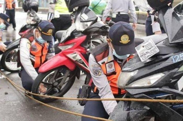 Petugas Suku Dinas Perhubungan Jakarta Utara mencabut pentil sejumlah sepeda motor yang parkir liar di tepi Jalan Gunung Sahari, Pademangan, Jakarta Utara.  