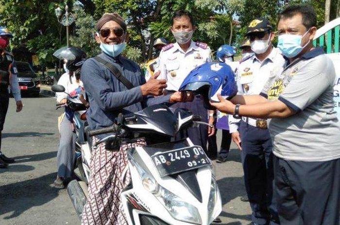 Wakil Bupati Bantul, Joko Purnomo memberikan helm pada pengguna jalan saat operasi simpatik di simpang tiga Sindon, Guwosari, Panjang, Jumat (12/03/2021). 