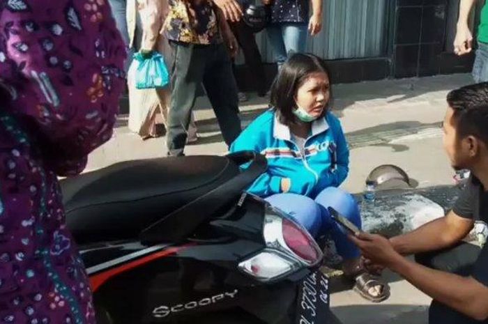 Wanita korban perampokan duduk di pinggir jalan setelah sebelumnya menabrak Innova