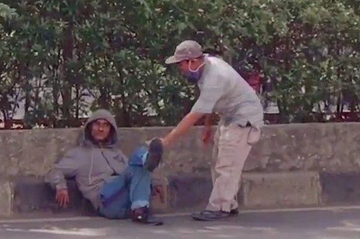 Viral di media sosial,  seorang pria duduk santai selonjoran di jalan dan  bersandar di pembatas jalan