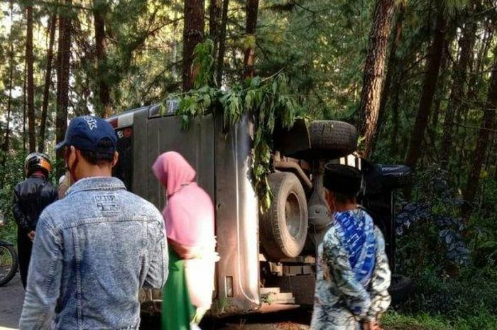 Isuzu Elf terguling dan nyender di pohon pinus