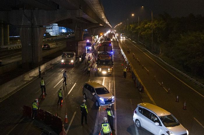 Petugas kepolisian mengarahkan kendaraan pribadi yang melintas di tol Jakarta-Cikampek untuk keluar melalui pintu tol Cikarang Barat 3, Jawa Barat (21/5/2020).