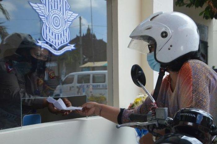 Seorang pengendara tampak sibuk melakukan perpanjangan SIM usai Polres Tabanan akhirnya melaunching layanan SIM Drive Thru di Mapolres Tabanan, Selasa 13 April 2021.