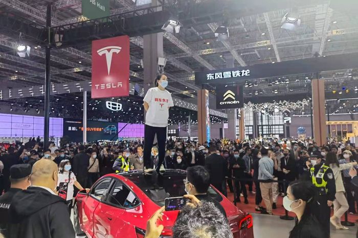 Seorang wanita protes dengan menginjak Tesla Model 3 di Shanghai Auto Show