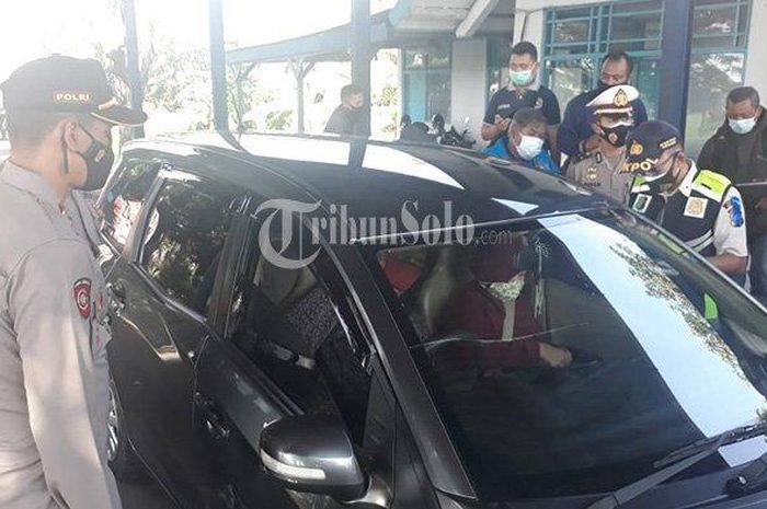 Personel Polres Sragen menanyai pengendara mobil dari luar daerah saat penyekatan di Jalan Solo-Ngawi, Sambungmacan, Sragen pada Selasa (20/4/2021). 