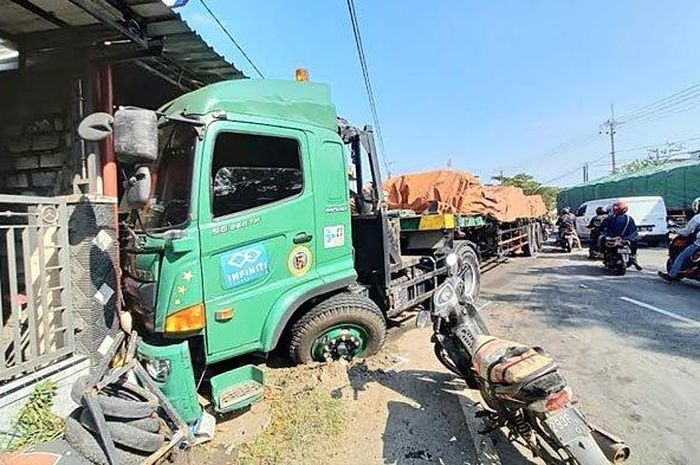Truk trailer menutup badan jalan usai menabrak rumah warga di Jalan Samirplapan, Kecamatan Duduksampeyan, Kabupaten Gresik, Jumat (30/4/2021). 