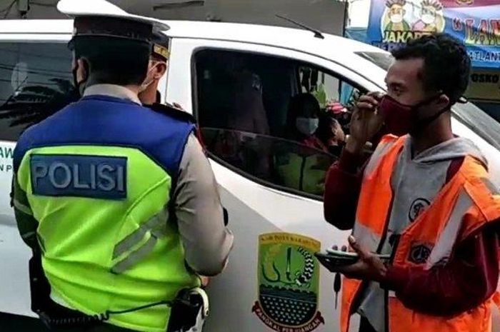 Petugas Satlantas Polsek Kalideres saat memeriksa Nissan Evalia pelat merah milik Pemkab Karawang yang terjaring penyekatan arus balik mudik di Jl Daan Mogot, Kalideres, Jakarta Barat