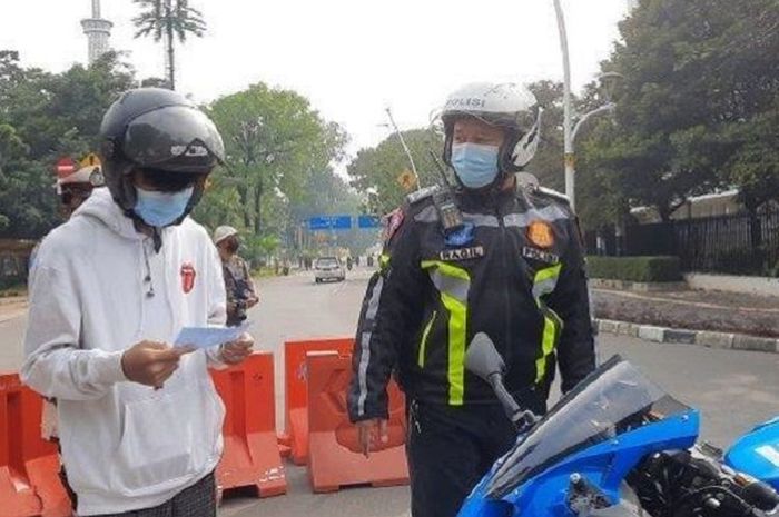 Remaja 16 tahun Rafly (kiri) ditilang polisi dalam razia Sunmori di Monas, Gambir, Jakarta Pusat, Minggu (7/3/2021). (WARTA KOTA Live.com/Desy Selviany)