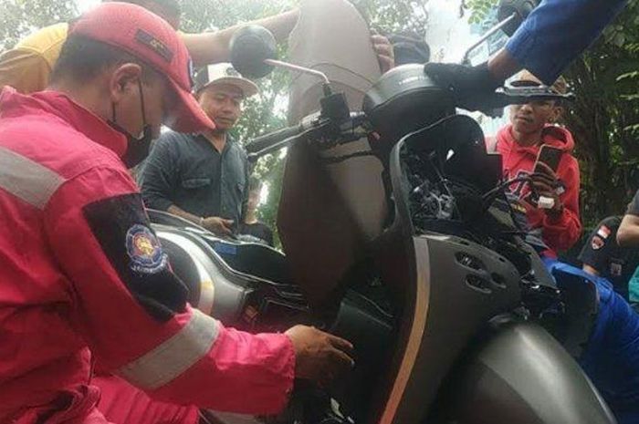 Tim Rescue Semut Ireng Damkar kota Malang tengan mempreteli bodi Honda Scoopy untuk mengevakuasi ular