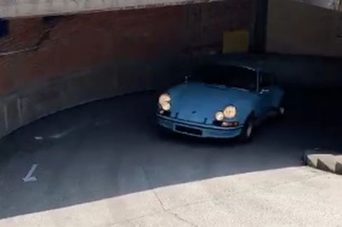 Porsche 911 Carrera RS sedang keluar dari parkiran basement.