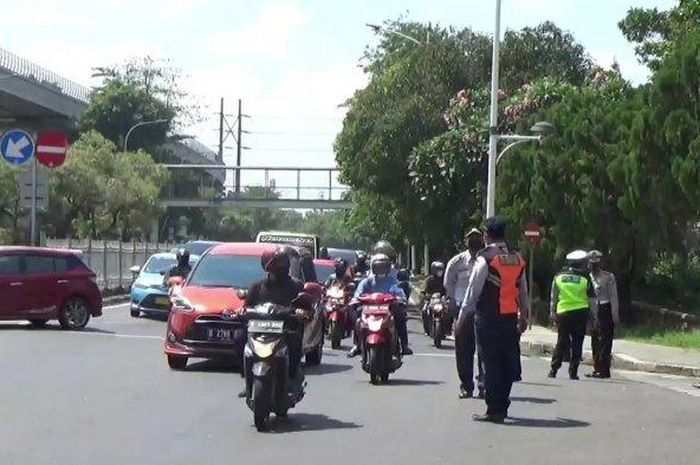 Petugas berjaga saat pemberlakukan ganjil genap di Jl Taman Mini 1 akses TMII, Cipayung, Jakarta Timur