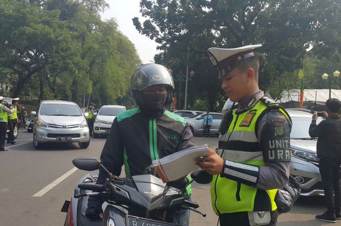 Polisi menilang pengendara sepeda motor yang belum membayar pajak kendaraan bermotor (PKB)-nya di Jalan Lapangan Banteng Selatan, Jakarta Pusat, Jumat (11/8/2017).(KOMPAS.com/NURSITA SARI)