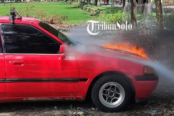 Mazda 323 terbakar di bagian kap mesin di lokasi parkir tempat wisata