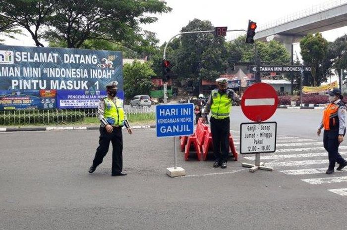 Petugas memasang plang ganjil genap di kawasan pintu utama TMII, Cipayung, Jakarta Timur