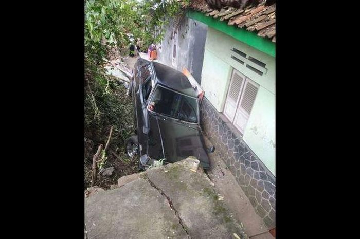 Posisi Toyota Corolla DX kejepit di halaman rumah warga setelah terjun dari jalan setinggi 1,5 meter di Kuningan, Jawa Barat