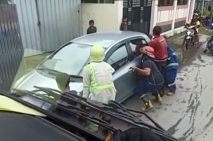 Petugas dan warga sekitar yang terpaksa meminggirkan Toyota Yaris yang parkir sembarangan.